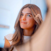Woman using a detangling comb, showcasing smooth hair and a smile, highlighting hair care and styling efficiency.