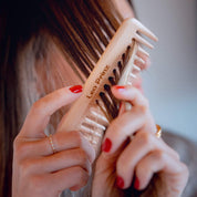 Woman using a natural wooden hair brush, showcasing its benefits for healthy hair and detangling without damage.